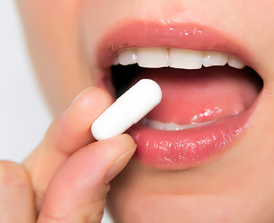Frau schluckt Tablette – Schmerzmittel lindern nur die Reizdarm-Symptome