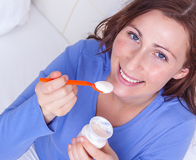 Frau isst Joghurt – Joghurt enthält nicht die spezifischen Bifidobakterien MIMBb75, die bei Reizdarm helfen