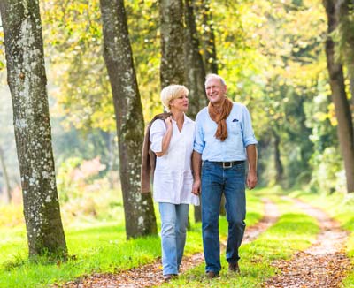 Älteres Paar beim Spaziergang im Wald – Bewegung beugt Blähungen vor